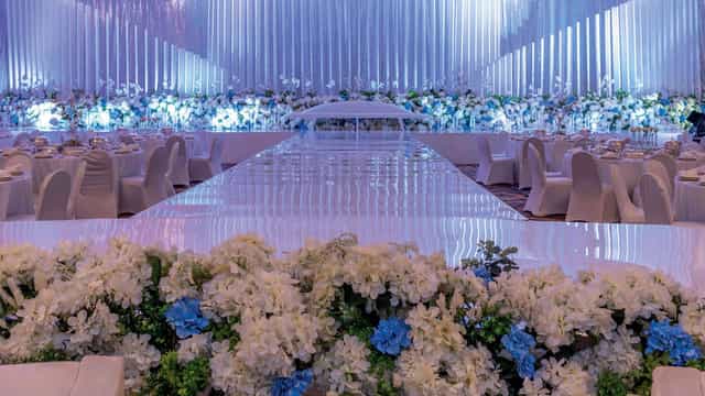 Luxury ballroom gala setup with reflective runway and floral decor for high-end wedding events.