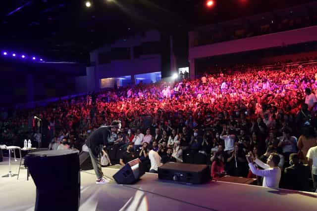 Keynote speaker on stage at a crowded conference, professional event lighting.