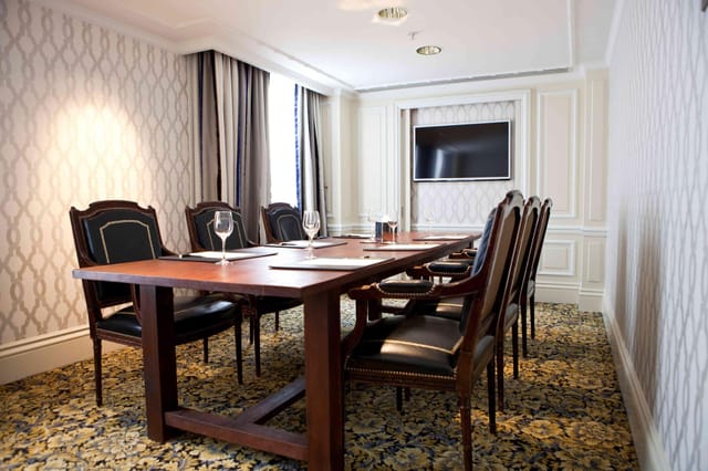 Business meeting room in Hotel Amsterdam Amstel with elegant wooden table and screen.