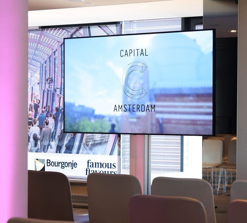 Modern conference space in Capital C Amsterdam with a large display screen for events.