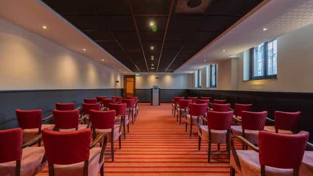 Council Chamber at Grand Hotel Amrâth Amsterdam, featuring red chairs for meetings and workshops.