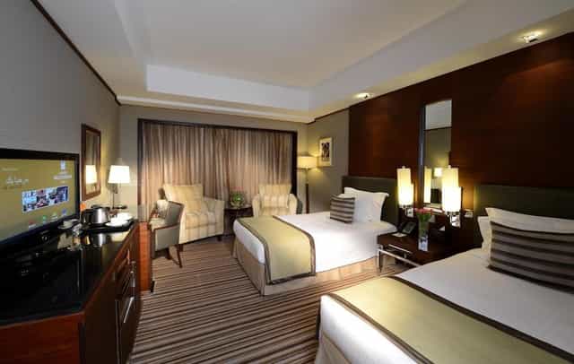 Grand Millennium Dubai twin suite with workspace for corporate business events.