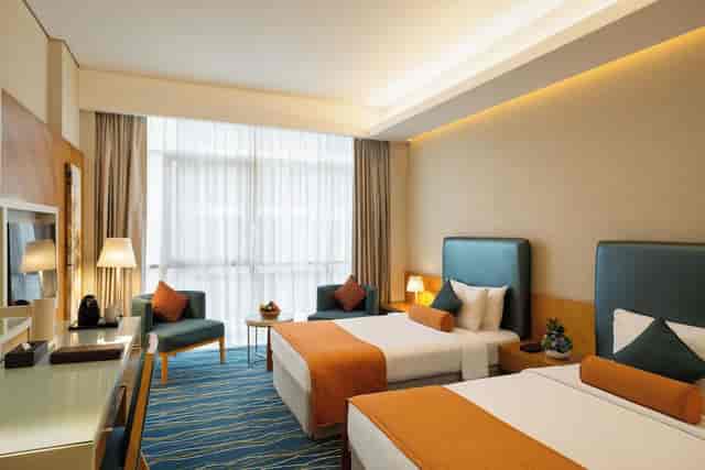 Modern twin-bed hotel suite with workspace for business travel and corporate event room blocks.