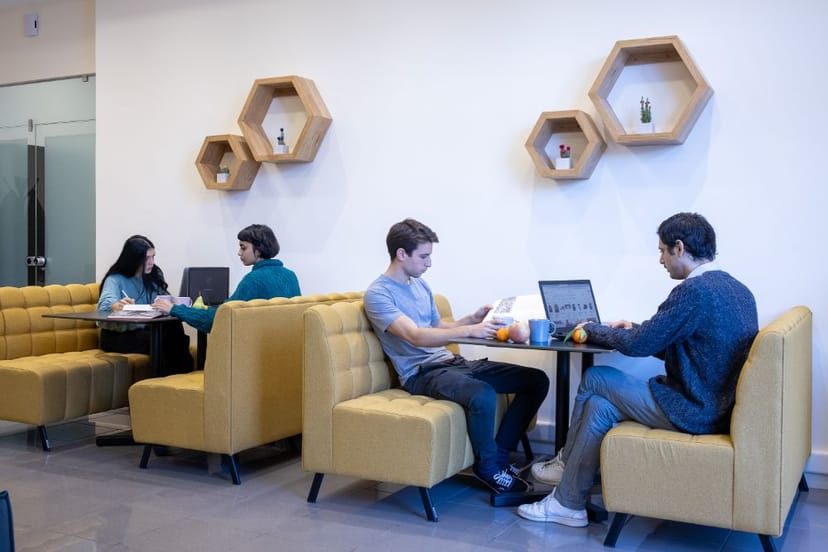 Modern coworking breakout room with yellow banquette seating for business meetings and workshops.