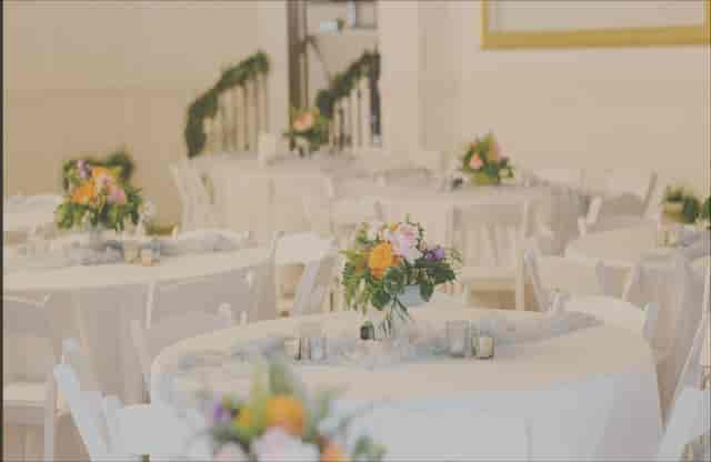 Ballroom wedding reception and gala dining area with round tables and floral centerpieces.