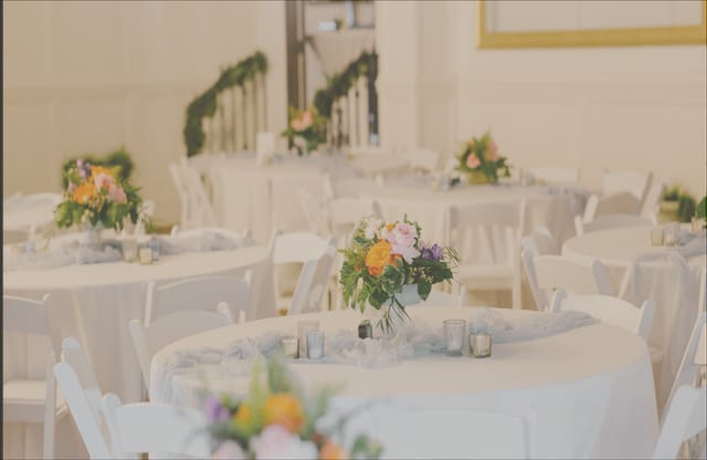 Ballroom wedding reception and gala dining area with round tables and floral centerpieces.