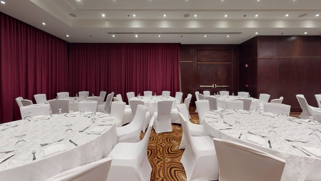 Najd Ballroom at Riyadh Marriott with burgundy drapes for luxury gala or corporate dinner events.