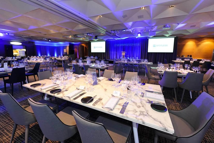 Corporate event banquet setup at ZINC Fed Sq with blue lighting and modern marble-topped tables.