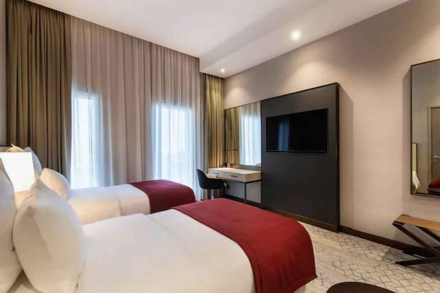 Modern twin guest room at Ramada Riyadh for business conferences and corporate meetings.