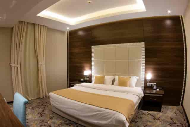 Modern hotel room with king bed and workspace for corporate event and business travel booking.
