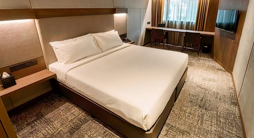 Minimalist bleisure hotel room with workspace for corporate travel and business events.