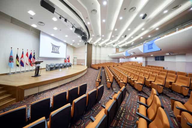 Tiered auditorium with plush seating for international conferences and professional plenary sessions.