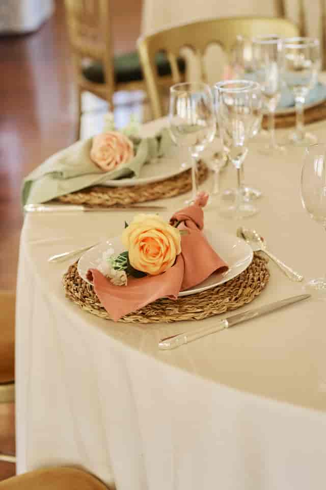 Bohemian-chic tablescape with rattan chargers at a luxury wedding or garden event.