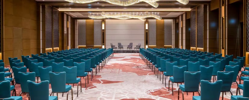Theater-style setup with teal seating at Al-Ghadeer for panel discussions and corporate events.