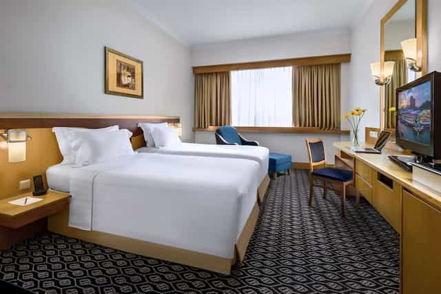 Twin guest room with workspace at Furama City Centre for business travel and group bookings.