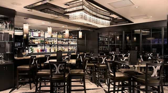 Upscale Morton's steakhouse bar with sleek high-top seating for corporate happy hour networking.