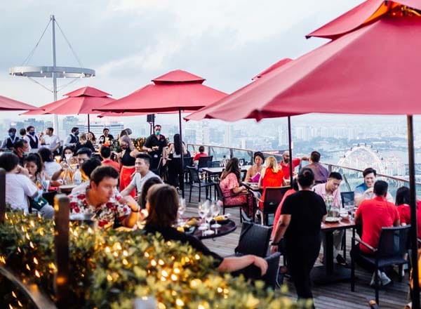 Rooftop Restaurant in CÉ LA VI Singapore with stylish red umbrellas for upscale events.
