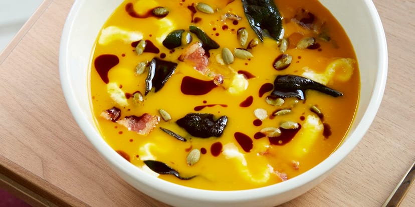Upscale autumn conference lunch: gourmet seasonal pumpkin soup with bacon garnish.