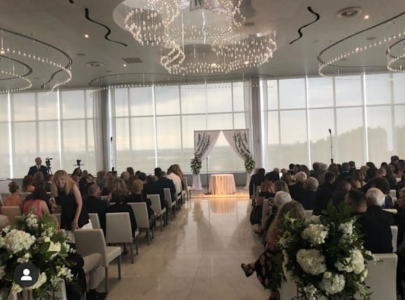 Modern rooftop ballroom wedding venue with floor-to-ceiling windows and custom lighting.