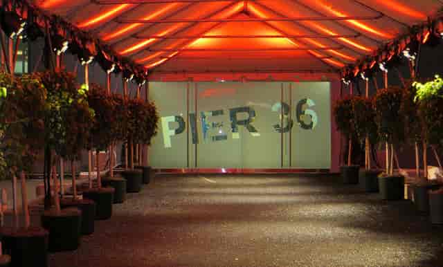 Tented entrance at Pier 36 NYC with greenery and uplighting for corporate events and gala arrivals.