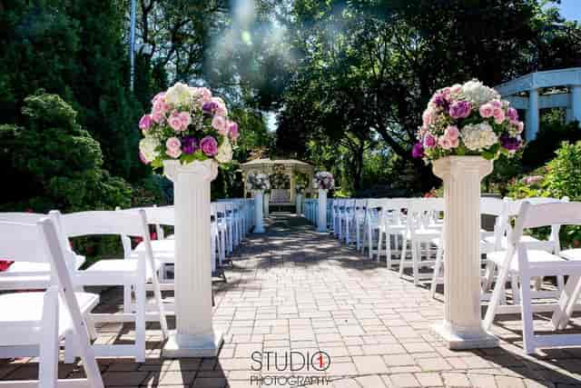 Villa Barone Manor outdoor wedding ceremony with white chairs and floral altar pedestals.