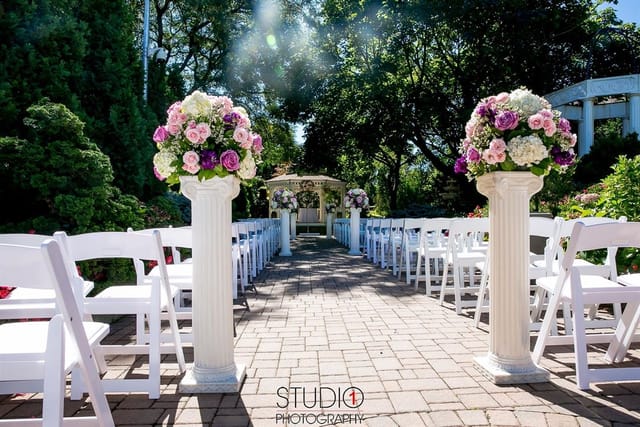 Villa Barone Manor outdoor wedding ceremony with white chairs and floral altar pedestals.