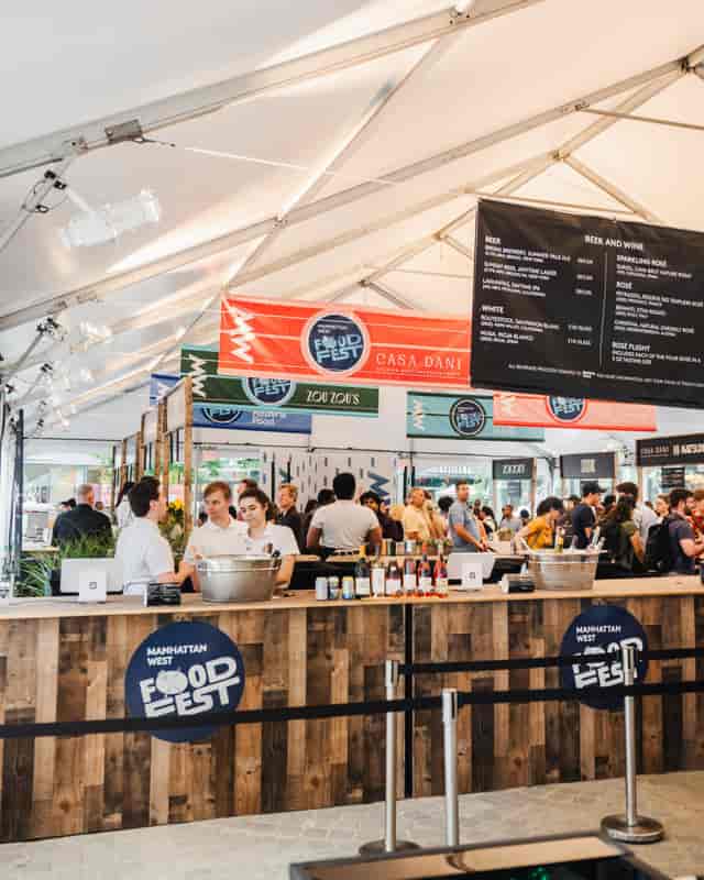 Manhattan West outdoor culinary festival: clear-span tent activation with rustic bars and branding.