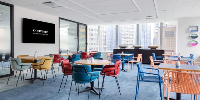 Modern meeting room with round tables and digital display for corporate events and workshops.