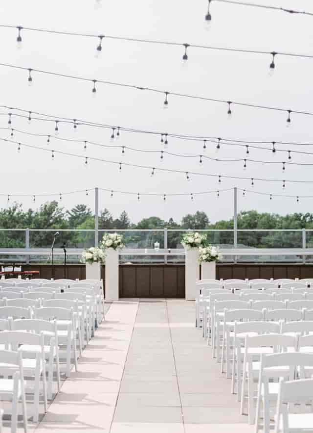 Outdoor wedding ceremony setup at The Heights Rooftop with bistro lighting and floral decor.
