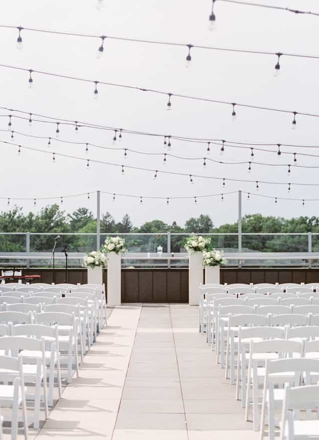Outdoor wedding ceremony setup at The Heights Rooftop with bistro lighting and floral decor.