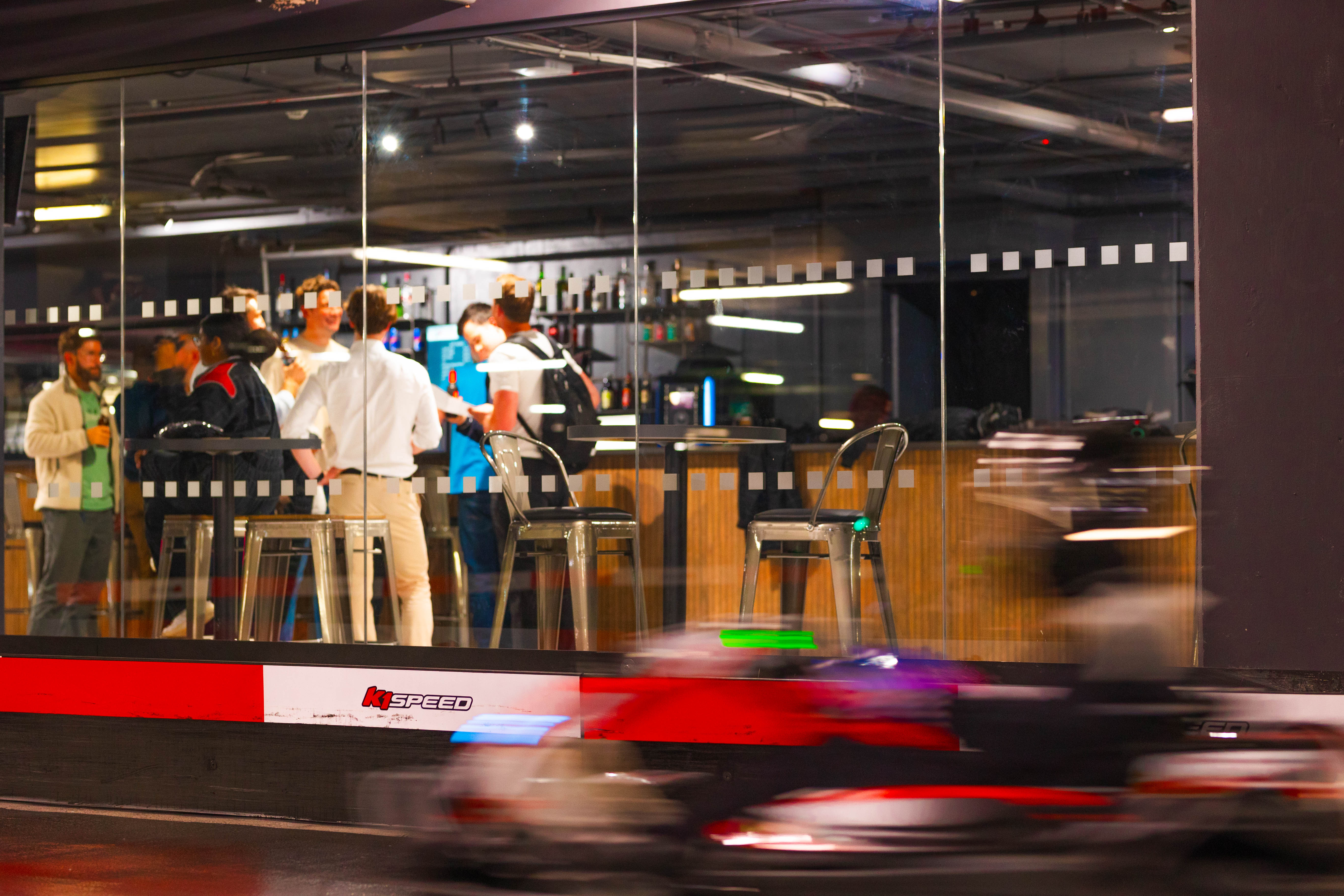 Indoor karting venue with vibrant networking event and modern glass walls at K1 Speed. - Banner
