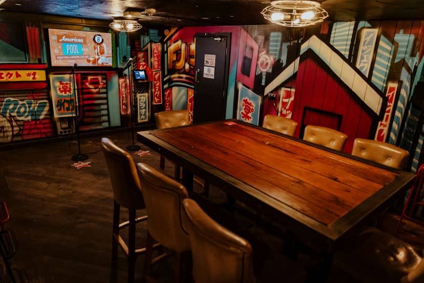 Karaoke room at Roxy Ball Room Leeds, featuring a rustic table and vibrant mural.