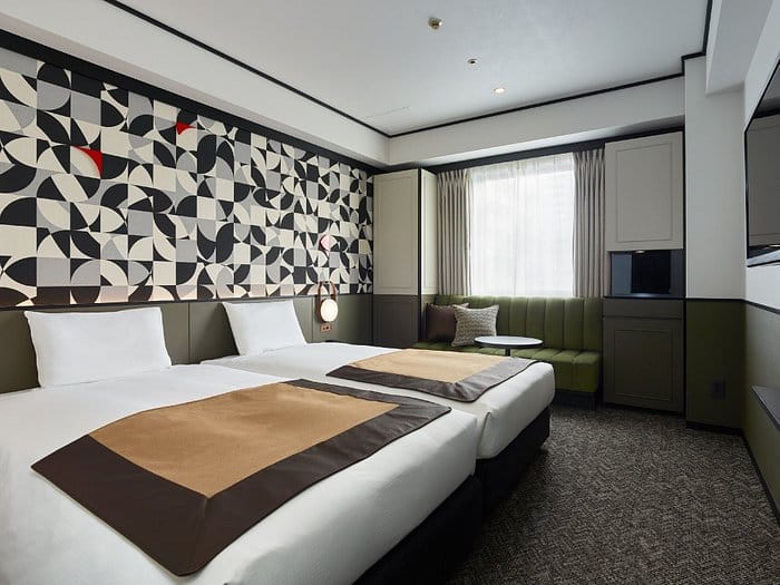 Modern hotel room with twin beds and workspace for corporate events and business travel.