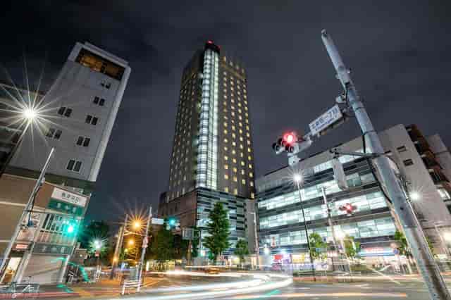 Hundred Stay Tokyo Shinjuku high-rise hotel at night for corporate travel and business meetings.