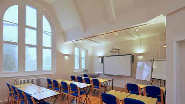 Well-lit workshop space in Rudolf Steiner House with tables, chairs, and projector.
