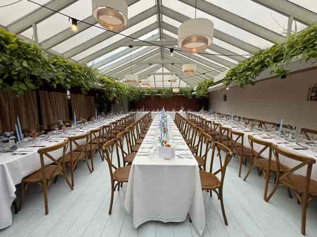 The Orangery glasshouse venue set for a sophisticated rehearsal dinner or corporate luncheon.