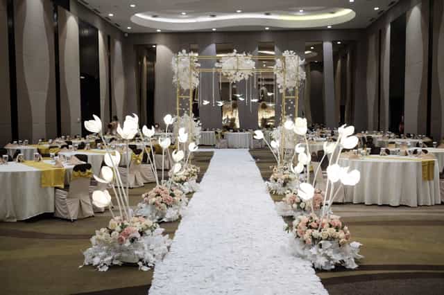 Ballroom wedding gala with dramatic floral lighting and aisle runner at Hotel Santika.