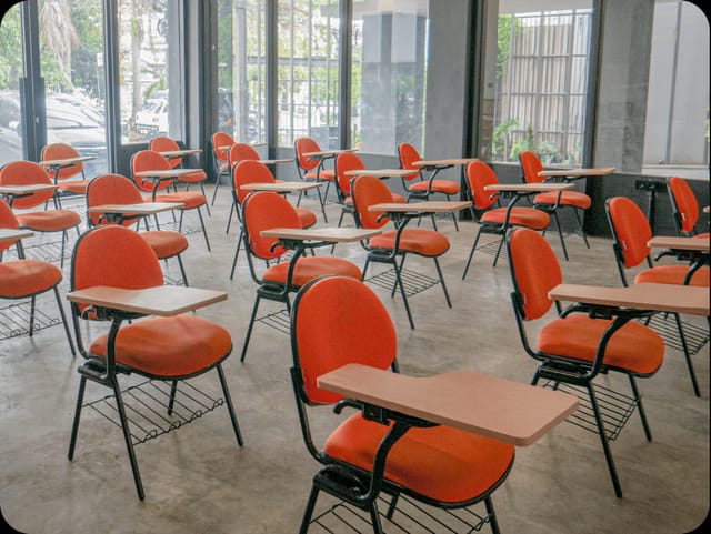Classroom-style meeting room with tablet armchairs for corporate training and academic workshops.
