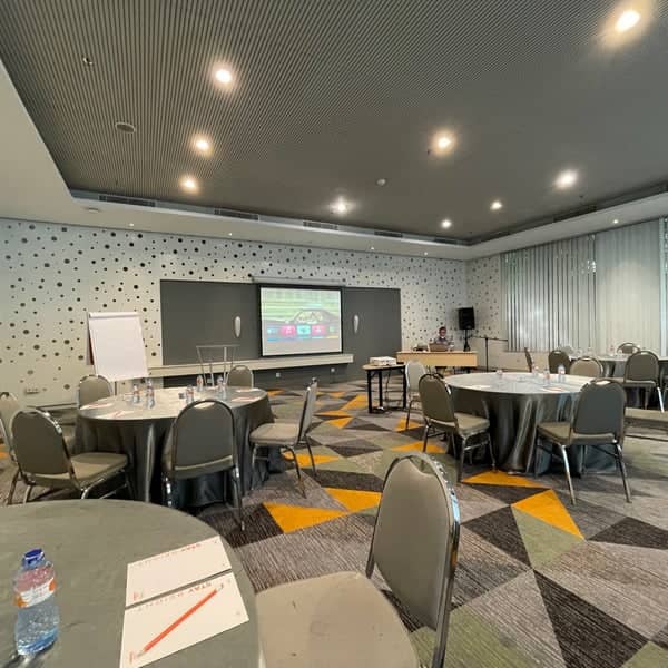 Modern meeting room at HARRIS Hotel Tebet with round tables for corporate events and workshops.