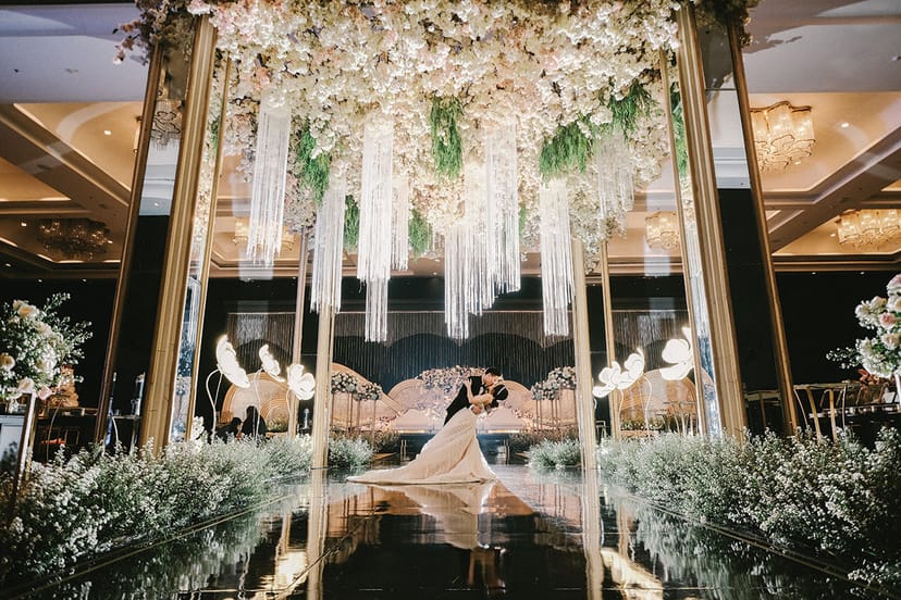 Luxury wedding in Lausanne Ballroom, Jakarta with grand hanging florals and mirrored stage.