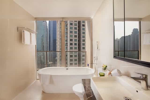 Upscale hotel bathroom with soaking tub and Jakarta city view for executive business events.