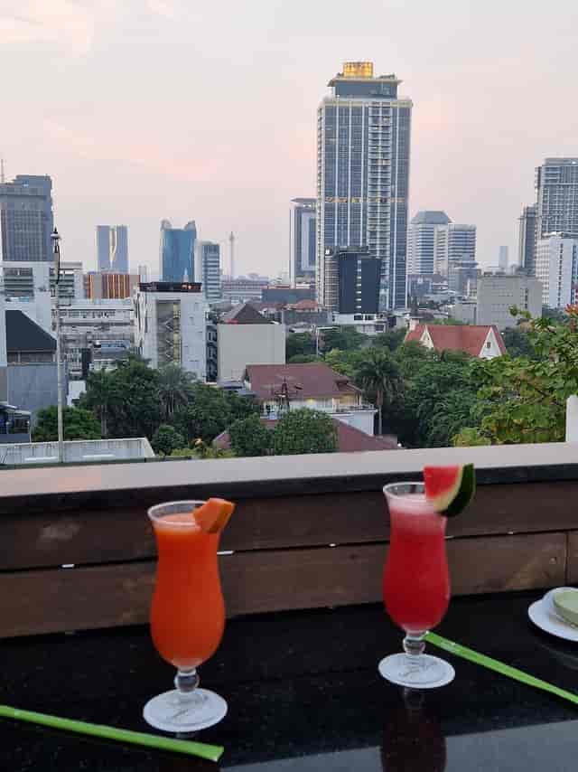 Rooftop bar at Jambuluwuk Thamrin Hotel with urban skyline for networking and cocktail events.