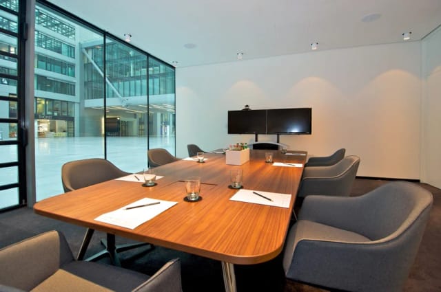 Minimalist boardroom with polished wood table for executive meetings and hybrid conferencing.