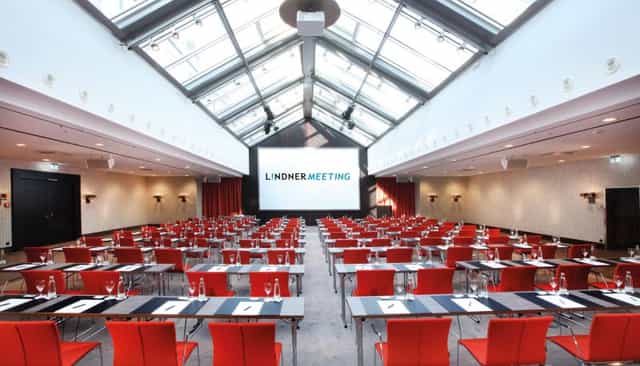 Classroom-style meeting room at Lindner Hotel Frankfurt with glass atrium for corporate training.