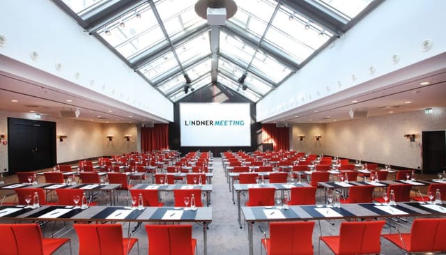 Classroom-style meeting room at Lindner Hotel Frankfurt with glass atrium for corporate training.