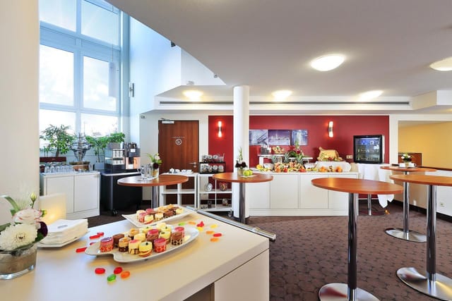 Stube pre-function area with cocktail tables and coffee station for networking events.