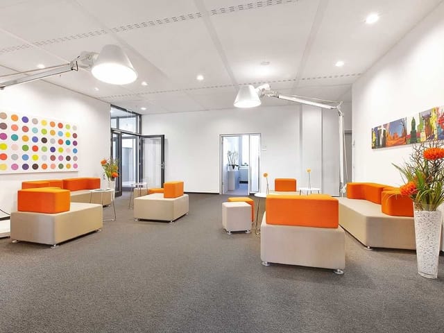 Modern Agendis Business Center breakout area with orange modular seating for networking events.