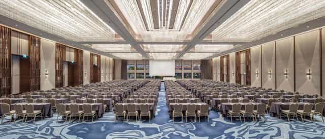 Hilton ballroom configured for a large-scale classroom plenary event with professional AV setup.