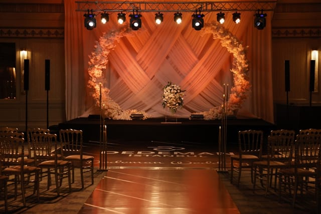 Dedeman Istanbul ballroom ceremony with floral arch, stage lighting, and runway for wedding events.