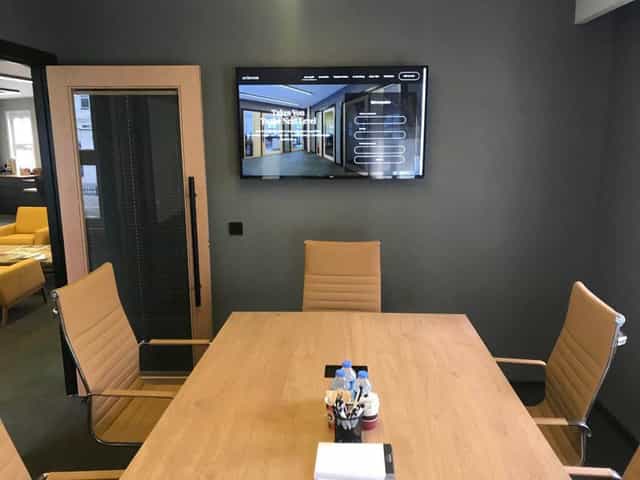 Modern huddle room with wall-mounted display for hybrid meetings and corporate breakout sessions.